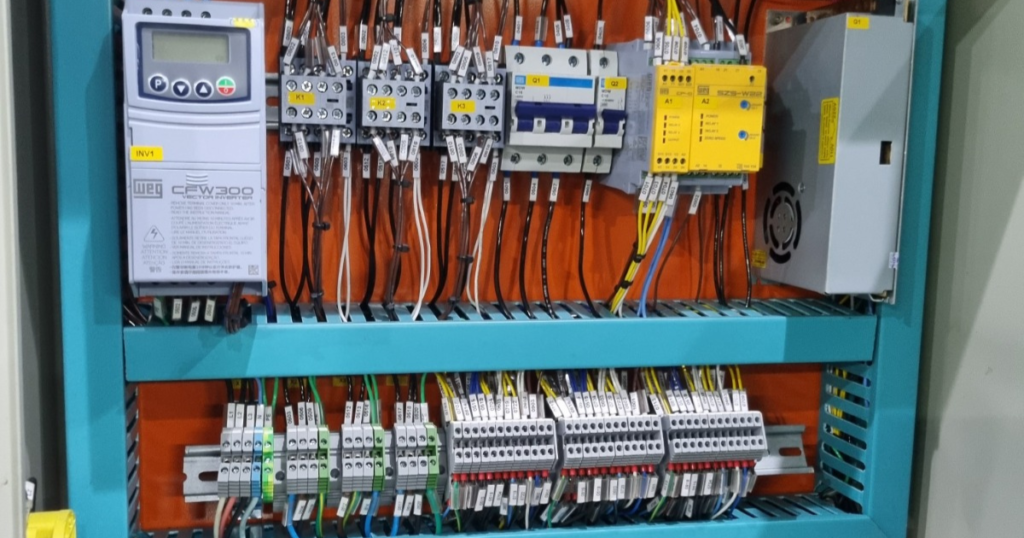 Interior de quadro de distribuição elétrica industrial com disjuntores, barramentos de cobre e fiação organizada.